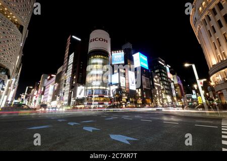 Autos, die bei Nacht an der Kreuzung bei Ginza vorbeifahren. Beliebtes gehobenes Einkaufsviertel von Tokio. Stockfoto