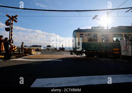 Zug der Enoshima Electric Railway durch Bahnübergang in der Nähe von Kamakurakokomae Station. Unter sonnenblauem Himmel. Stockfoto