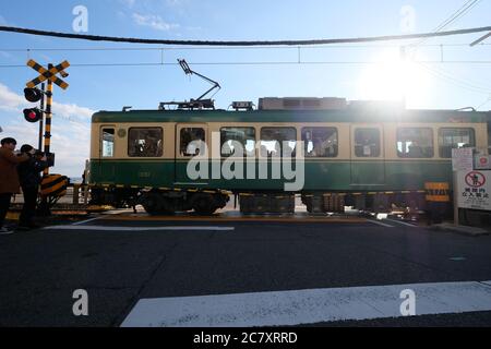 Zug der Enoshima Electric Railway durch Bahnübergang in der Nähe von Kamakurakokomae Station. Unter sonnenblauem Himmel. Stockfoto