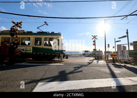 Zug der Enoshima Electric Railway durch Bahnübergang in der Nähe von Kamakurakokomae Station. Unter sonnenblauem Himmel. Stockfoto