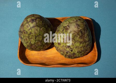 Draufsicht auf reife Puddingäpfel auf blauem Hintergrund. Frische und organische Puddingäpfel auf einer Holzschüssel. Stockfoto