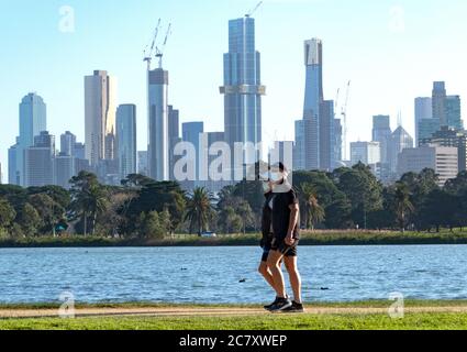 Coronavirus Melbourne Covid-19. Menschen mit Schutzmaske laufen durch Melbourne mit der Skyline der Stadt im Hintergrund. Stockfoto