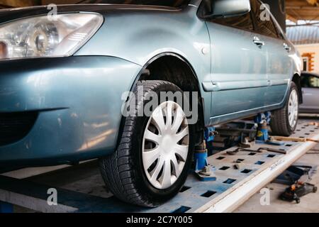 Ein blaues Auto wird zur Reparatur in einem Autoservice auf einen Aufzug gehoben. Stockfoto