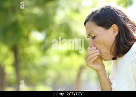 Kranke Erwachsene Frau hustet im Sommer im Park stehen Stockfoto