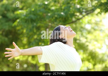Glückliche Erwachsene Frau atmen frische Luft ausstreckt Arme im Park im Sommer Stockfoto