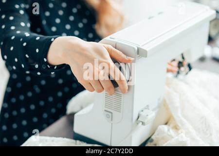 Näherin näht die Kleidung und legt den Faden in die Nadel. Arbeitsplatz des Schneiders. Menschen, Handarbeiten und Schneiderkonzept - Schneiderin Frau Einfädeln Nadel Stockfoto