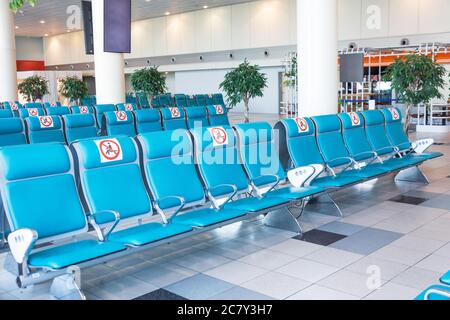 Reihen türkisfarbener Sitze im Warteraum mit einem Schild angebracht- nicht besetzen, nicht setzen. Konzept der sozialen Distanz, Pandemievorsorge Stockfoto