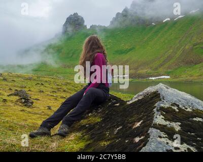 Junge Frau Wanderer mit langen braunen Haaren Blick auf geheimnisvolle Blick auf schöne König und Königin Hornbjarg Klippen in West-Fjorde, abgelegenen Naturschutzgebiet Stockfoto