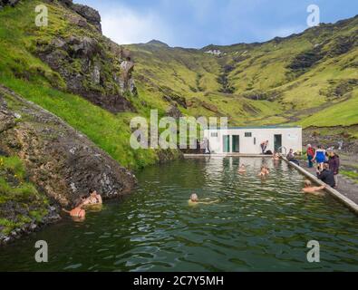 Südisland, Seljavellir, 4. Juli 2018: Menschen schwimmen und genießen Sie grünes warmes Wasser in Seljavallalaug geheimen geothermischen Pool hiden im Tal mit