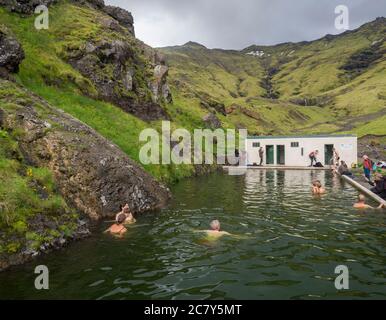 Südisland, Seljavellir, 4. Juli 2018: Menschen schwimmen und genießen Sie grünes warmes Wasser in Seljavallalaug geheimen geothermischen Pool hiden im Tal mit