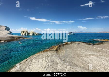 Mann schwimmt von einem Katamaran in klarem Wasser der Sarakiniko Bucht, Milos Insel, Kykladen, Griechenland Stockfoto