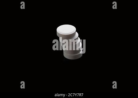 Fünf weiße Pillen angeordnet, um auf schwarzem Hintergrund isoliert Stapel. Medizinisches Konzept. Stockfoto