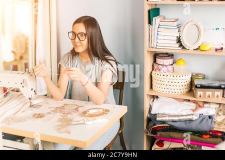 Ziemlich junge Schneiderin nimmt Dekorationen Stockfoto