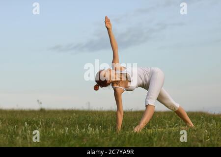 Erwachsene Frau, die Yoga im Sommer im Frühling auf dem Land macht Stockfoto