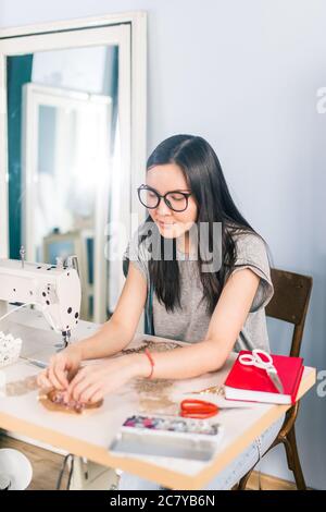 Ziemlich junge Schneiderin nimmt Dekorationen Stockfoto