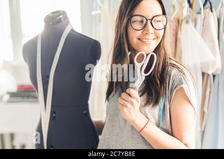 Hübsche junge Schneiderin packte ein neues Kleidungsstück als Geschenk in der Nähwerkstatt. Stockfoto