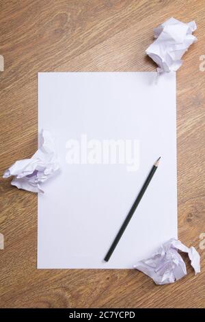 Bleistift auf klarem weißem Papier mit zerbröckeligen Papierkugeln auf Holztischhintergrund Stockfoto