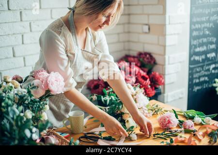 Cute konzentriert junge weibliche Florist in Gläser im Blumenladen arbeiten Stockfoto