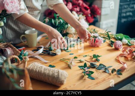 Cute konzentriert junge weibliche Florist in Gläser im Blumenladen arbeiten Stockfoto