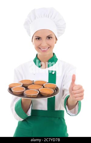 Junge Chefin Frau in Uniform halten Tablett mit Muffins und Daumen nach oben isoliert auf weißem Hintergrund Stockfoto