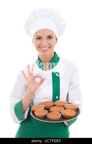 Junge Chefin Frau in Uniform halten Tablett mit Muffins und zeigt ok Zeichen isoliert auf weißem Hintergrund Stockfoto