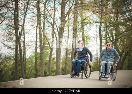 Zwei behinderte Freunde reiten im Park und genießen Stockfoto