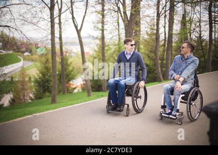 Zwei behinderte Freunde reiten im Park und genießen Stockfoto