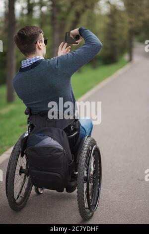 Ungültige Mann auf einem Rollstuhl sitzen und genießen Sie einen Spaziergang im freien Stockfoto