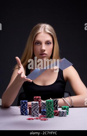 Junge attraktive Frau wirft Spielkarten im Casino Stockfoto