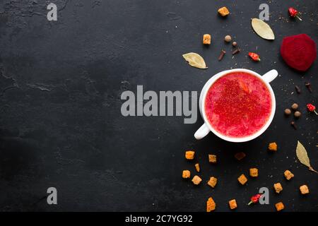 Borscht mit Zwieback, rotem getrocknetem Pfeffer und Lorbeerblatt auf schwarzem Hintergrund mit Platz für Text Stockfoto