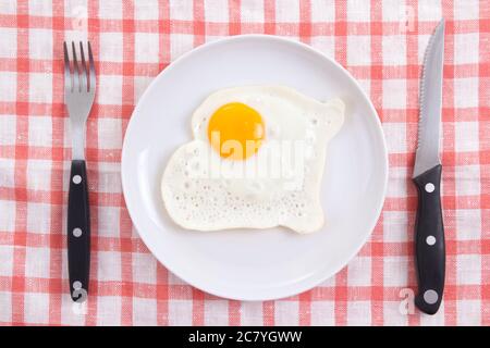Spiegelei in weißer Platte mit Gabel und Messer auf dem Tisch Stockfoto