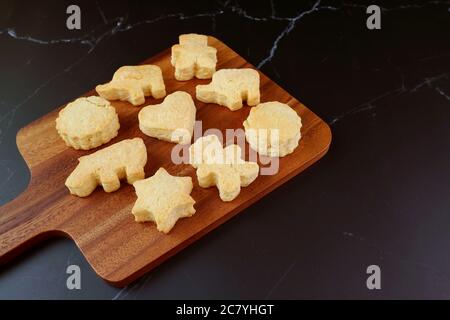 Frisch gebackene hausgemachte Kekse auf Holzbrett isoliert auf schwarzem Tisch Stockfoto