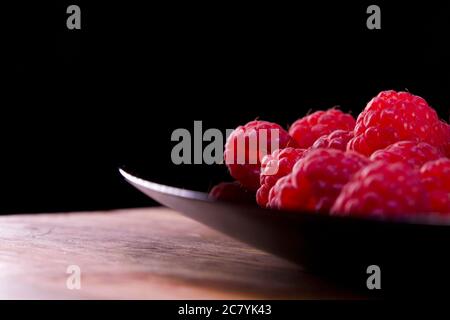 Himbeeren Komposition auf schwarzem Teller und schwarzem Hintergrund. Frische und schmackhaft aussehende Bio-Lebensmittel für Veganer in der Sommersaison. WaldHimbeere fru Stockfoto