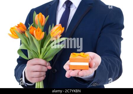 Vorschlag - Geschenkbox mit Ehering und Blumen in männlichen Händen isoliert auf weißem Hintergrund Stockfoto