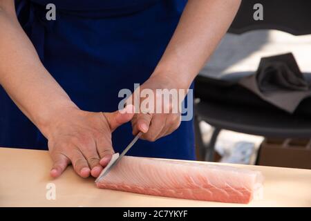 Japanischer Meisterkoch bereitet Sashimi aus frischem Fisch zu. Selektiver Fokus auf Menschenhänden. Stockfoto