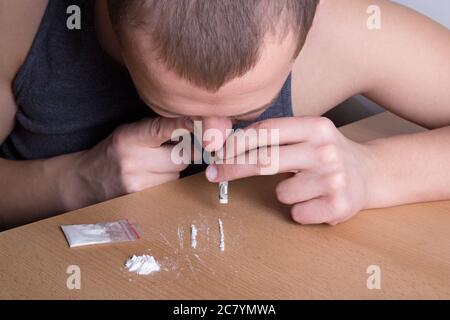 Süchtig junger Mann schnaubt Heroin aus dem Tisch Stockfoto