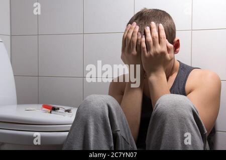 Junger Mann mit Steinen und Heroinsucht im Badezimmer Stockfoto