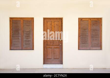 Gelbe Wand mit Retro-Tür und zwei Fenstern Stockfoto