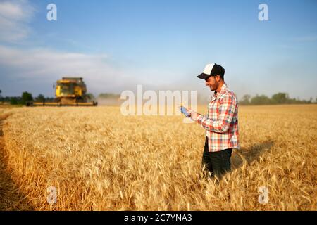 Präzisionslandwirtschaft. Landwirt hält Tablet für Mähdrescher Führung und Steuerung mit modernen Automatisierungssystem. Agronom mit Online-Daten Stockfoto