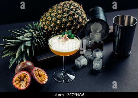Cocktail aus Ananas und Passionsfrucht mit Fruchtfleisch in einem Glas auf schwarzem Hintergrund. Selektiver Fokus. Stockfoto
