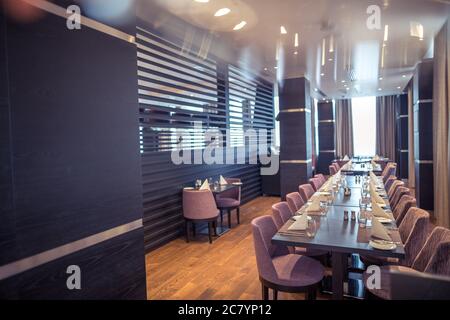 Halb beleuchtete Halle im Loft-Stil in einem mexikanischen Restaurant mit offener Küche im Hintergrund. Vor der Küche gibt es Holztische mit mu Stockfoto