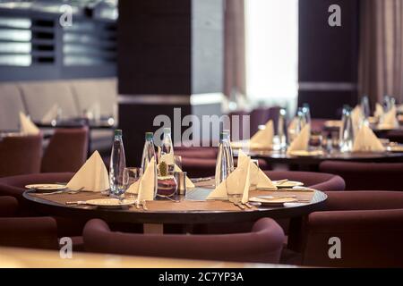 Halb beleuchtete Halle im Loft-Stil in einem mexikanischen Restaurant mit offener Küche im Hintergrund. Vor der Küche gibt es Holztische mit mu Stockfoto