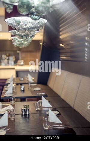 Halb beleuchtete Halle im Loft-Stil in einem mexikanischen Restaurant mit offener Küche im Hintergrund. Vor der Küche gibt es Holztische mit mu Stockfoto