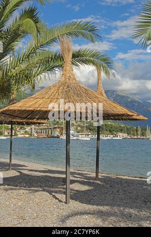 Große Strohsonnenschirme und Palmenblätter am Strand in Montenegro Stockfoto