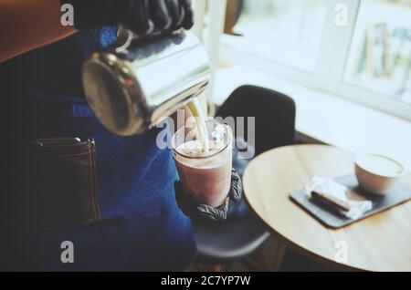 Barista macht rosa Matcha Latte mit Milch. Barkeeper bereitet leckere Getränk.verschwommenes Bild, selektiver Fokus Stockfoto