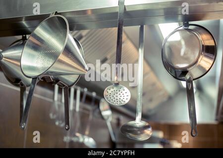Küche Messingutensilien, Küchenzubehör. Hängende Kupfer Küche mit weißen Fliesen Wand Stockfoto
