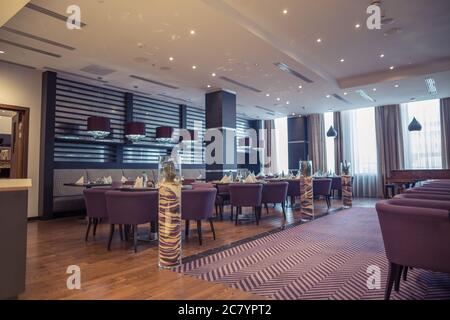 Halb beleuchtete Halle im Loft-Stil in einem mexikanischen Restaurant mit offener Küche im Hintergrund. Vor der Küche gibt es Holztische mit mu Stockfoto