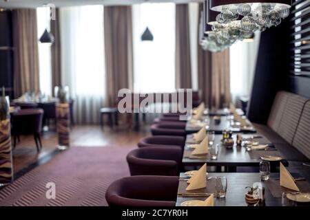 Halb beleuchtete Halle im Loft-Stil in einem mexikanischen Restaurant mit offener Küche im Hintergrund. Vor der Küche gibt es Holztische mit mu Stockfoto