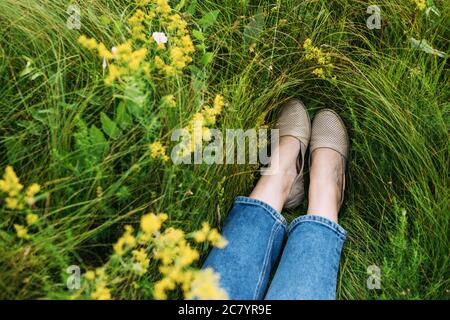 Die Füße der Frau liegen auf Gras. Sommerruhe. Draufsicht. Stockfoto