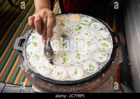 Hand und Löffel Kommissionierung Kanom Krok oder Art von Thai Süßfleisch, Thai Dessert auf einem Tablett, Herstellung von Süßigkeiten Stockfoto